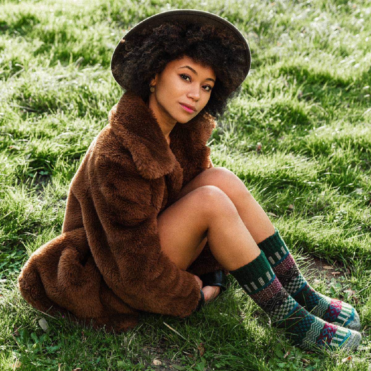 Unisex Svea Wool Green Nordic Socks featured on a woman sitting on grass, wearing a fur coat and hat.