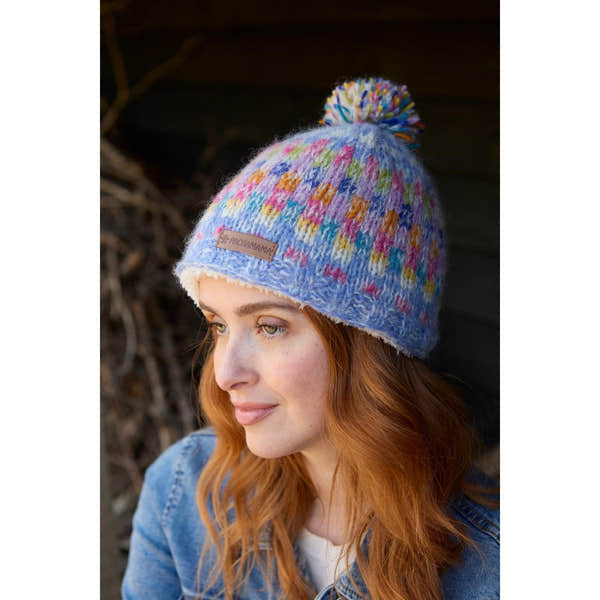 Pachamama Arundel Bobble Beanie Sky, colorful knit hat with pom-pom, soft fleece lining, and branded leather patch.