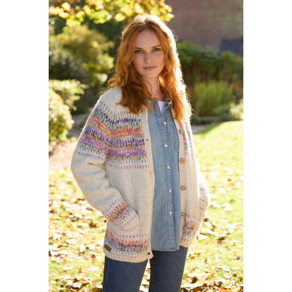 Woman wearing Pachamama Arundel Cardigan in oatmeal with multicolored knit details, outdoors in fall setting.