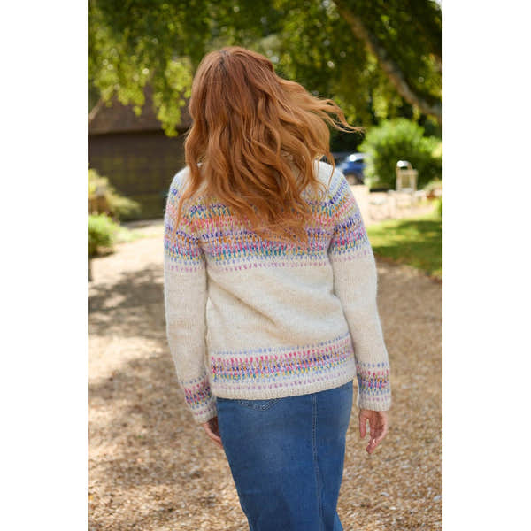 Pachamama Arundel Cardigan in oatmeal with colorful Fair Isle pattern, long sleeves, cozy knit, worn outdoors on a gravel path.