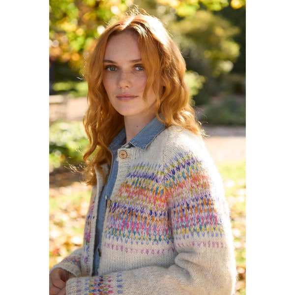 Pachamama Arundel Cardigan in oatmeal with colorful knit pattern, worn over denim shirt, outdoors in autumn.