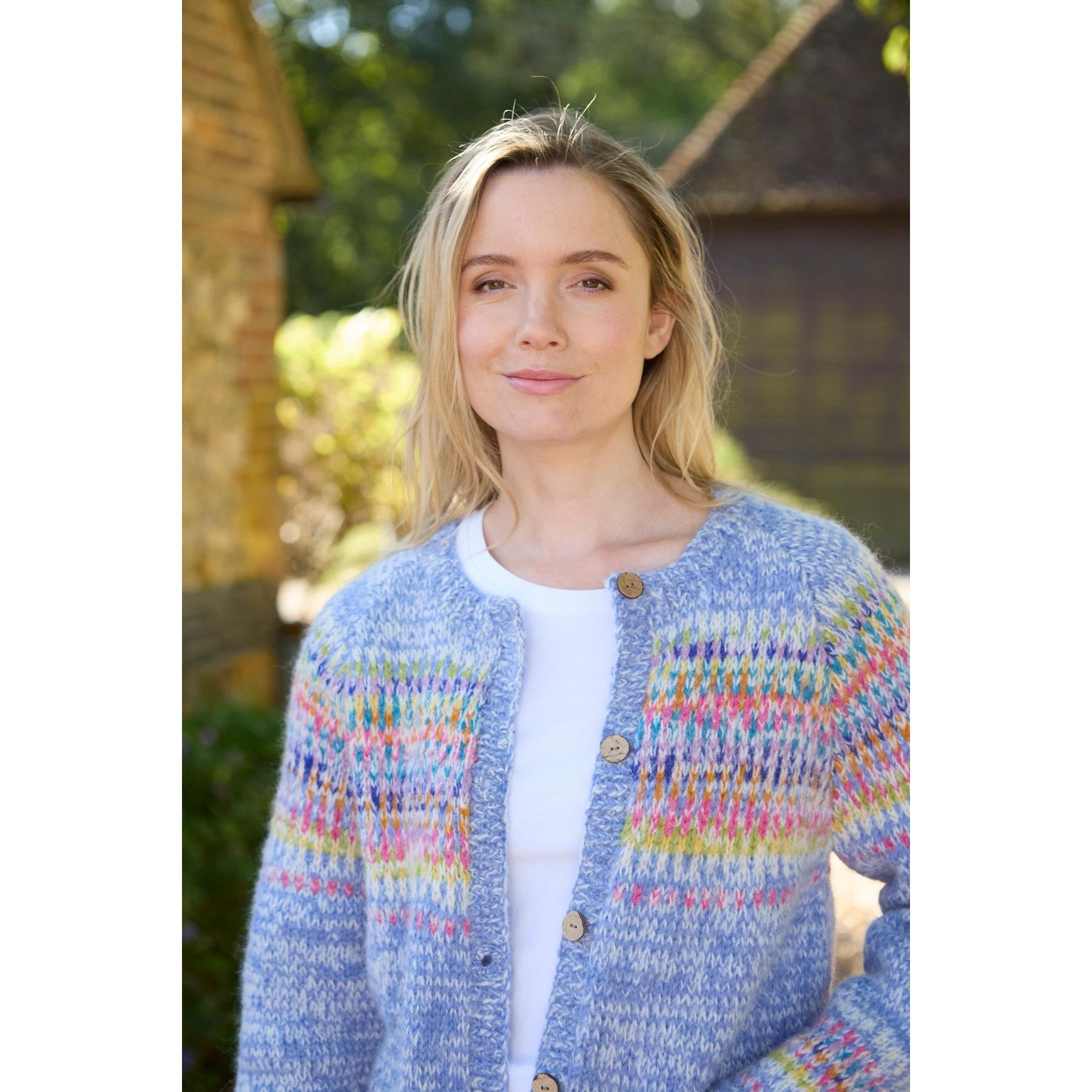 Pachamama Arundel Sky cardigan in pastel knit with colorful patterns, worn by a woman outdoors on a sunny day.