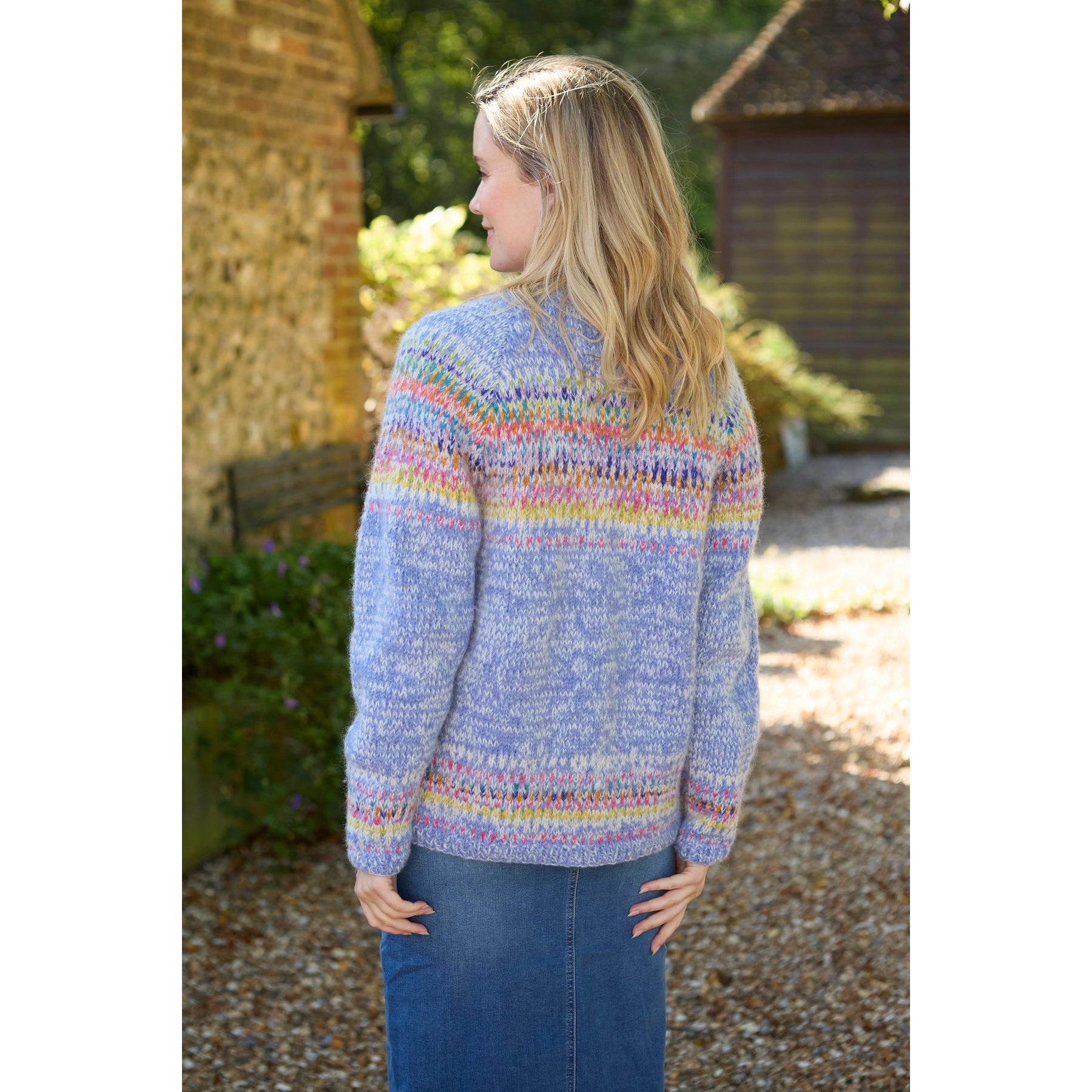Woman wearing Pachamama Arundel Cardigan in Sky, colorful knitted sweater with pastel hues, outdoors in sunlight.