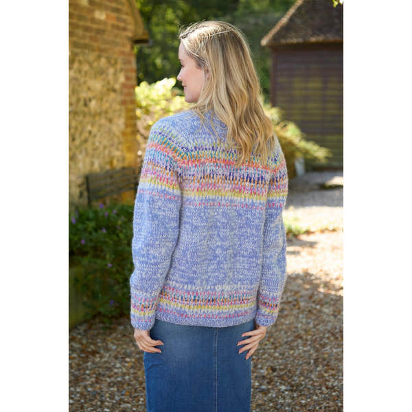 Woman wearing Pachamama Arundel Cardigan in Sky, colorful knitted sweater with pastel hues, outdoors in sunlight.