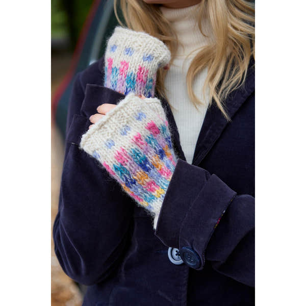 Pachamama Arundel Handwarmer Oatmeal, cozy knitted mittens with colorful patterns, worn by a person in a navy coat outdoors.