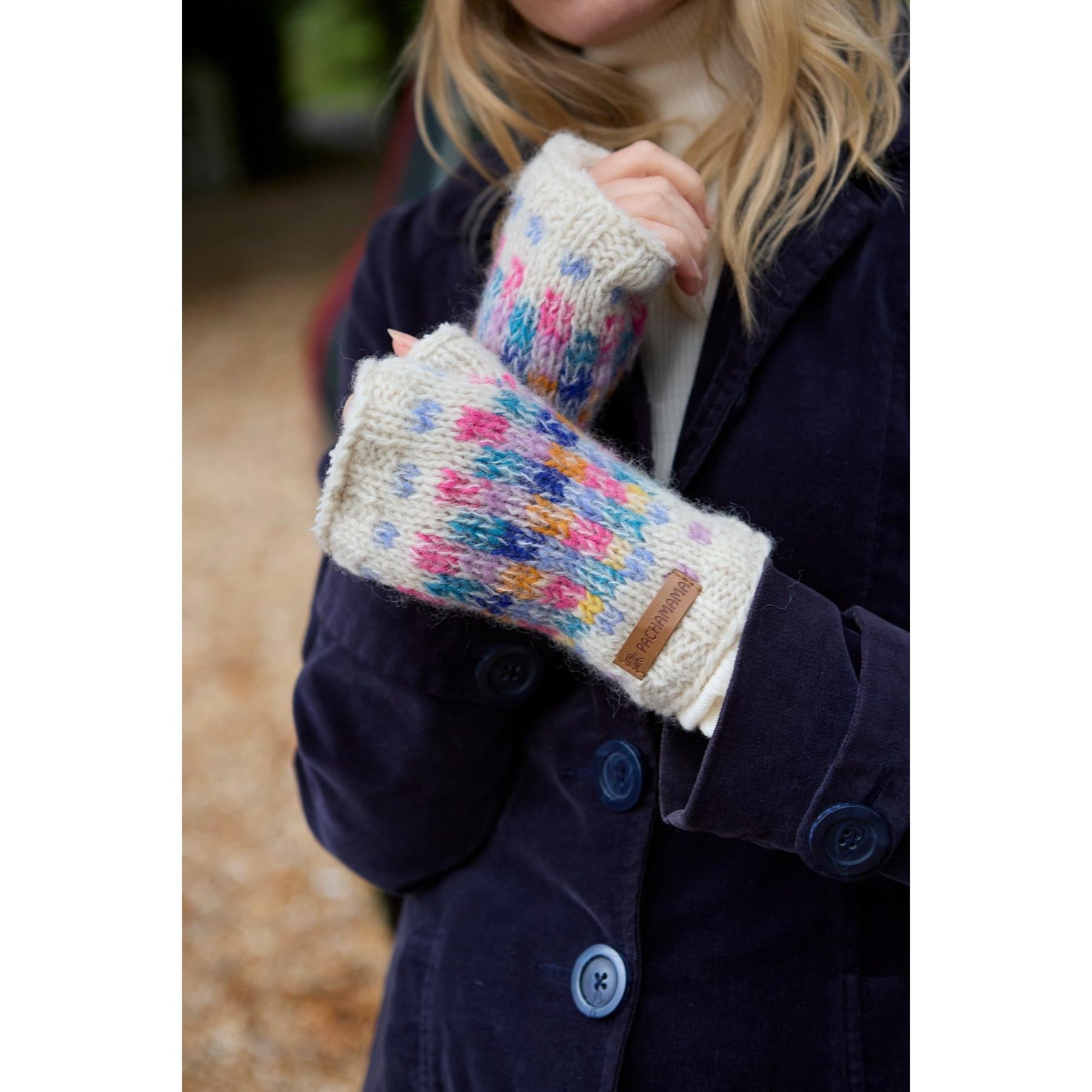 Pachamama Arundel Handwarmer Oatmeal, cozy knitted wool gloves with colorful pattern, worn by a person outdoors.
