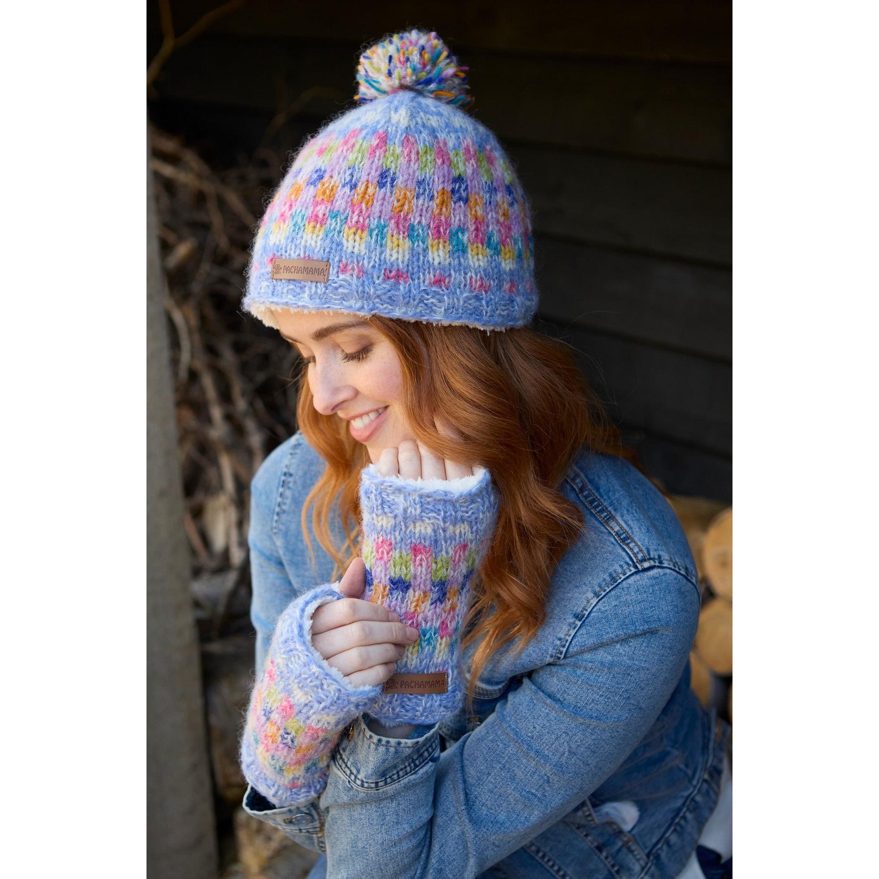 Woman wearing Pachamama Arundel Sky knit beanie and matching fingerless gloves, outdoors.