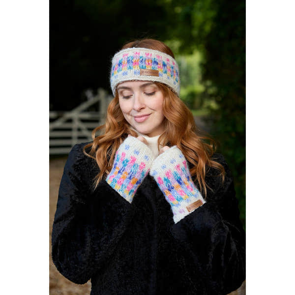 Young woman wearing Pachamama Arundel oatmeal headband and matching gloves outdoors, cozy winter accessories with colorful knit pattern.
