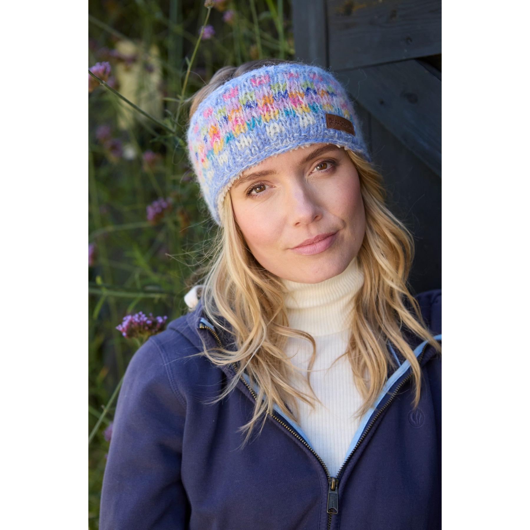Pachamama Arundel Headband Sky, colorful knitted winter headband worn outdoors by woman, lightweight and cozy accessory.
