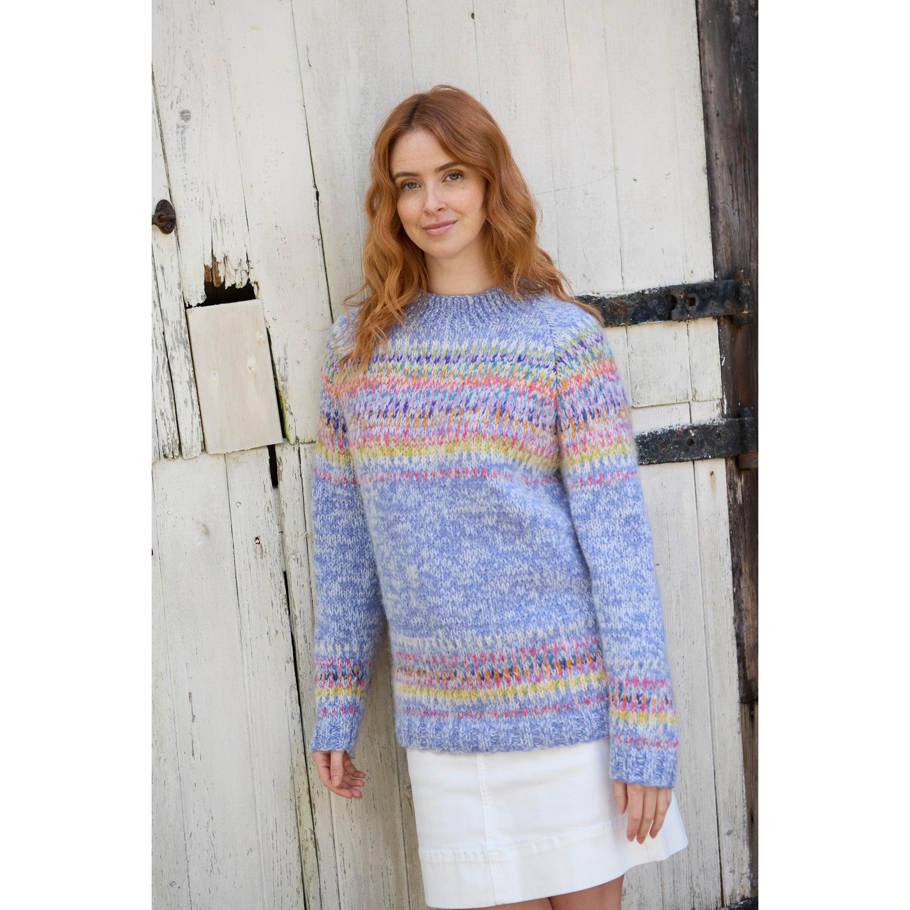 Pachamama Arundel Sweater Sky, colorful knit sweater with pastel shades, long sleeves, and crew neckline, worn by a woman outdoors.