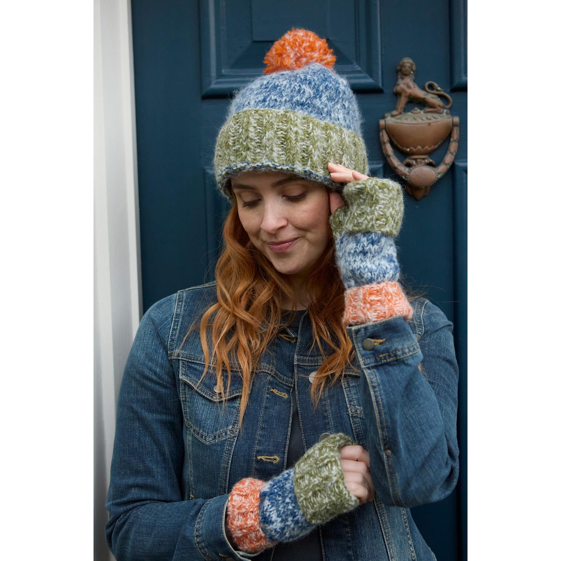 Pachamama Berlin blue and multicolor bobble beanie with pom-pom, knit cuff, and color-block design on model.