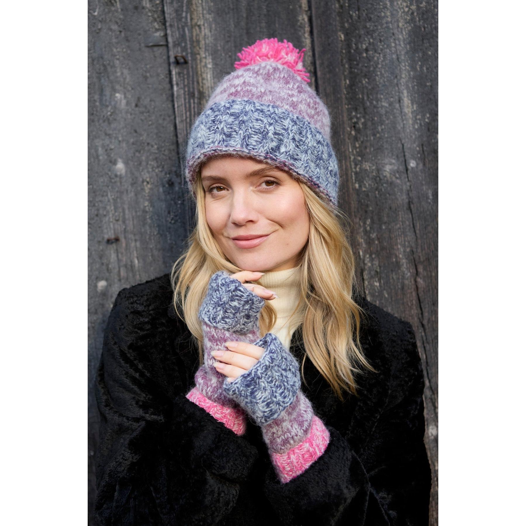 Pachamama Berlin purple bobble beanie and fingerless gloves, cozy knit winter accessories for women, against wooden background.