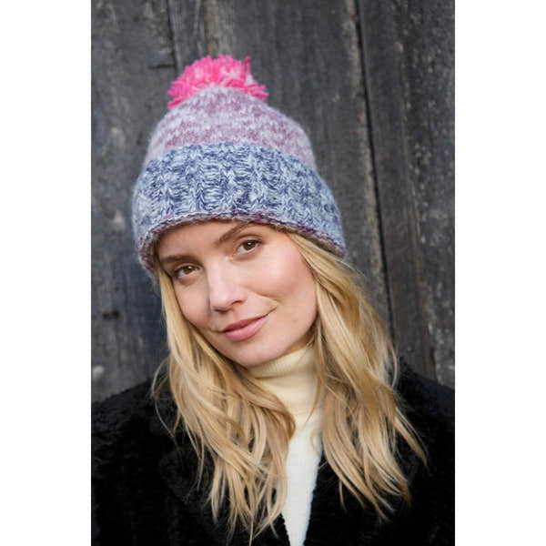 Pachamama Berlin purple bobble beanie hat with multicolored knit design and pom-pom, worn by a woman outdoors.