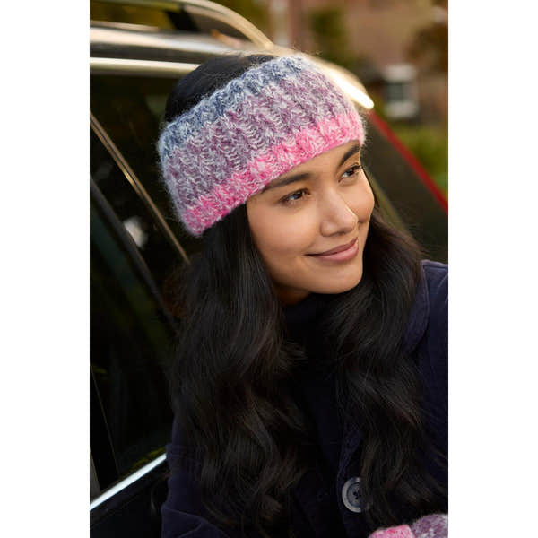 Pachamama Berlin purple headband worn by a woman with long dark hair, knitted design, variegated pink, gray, and white colors.