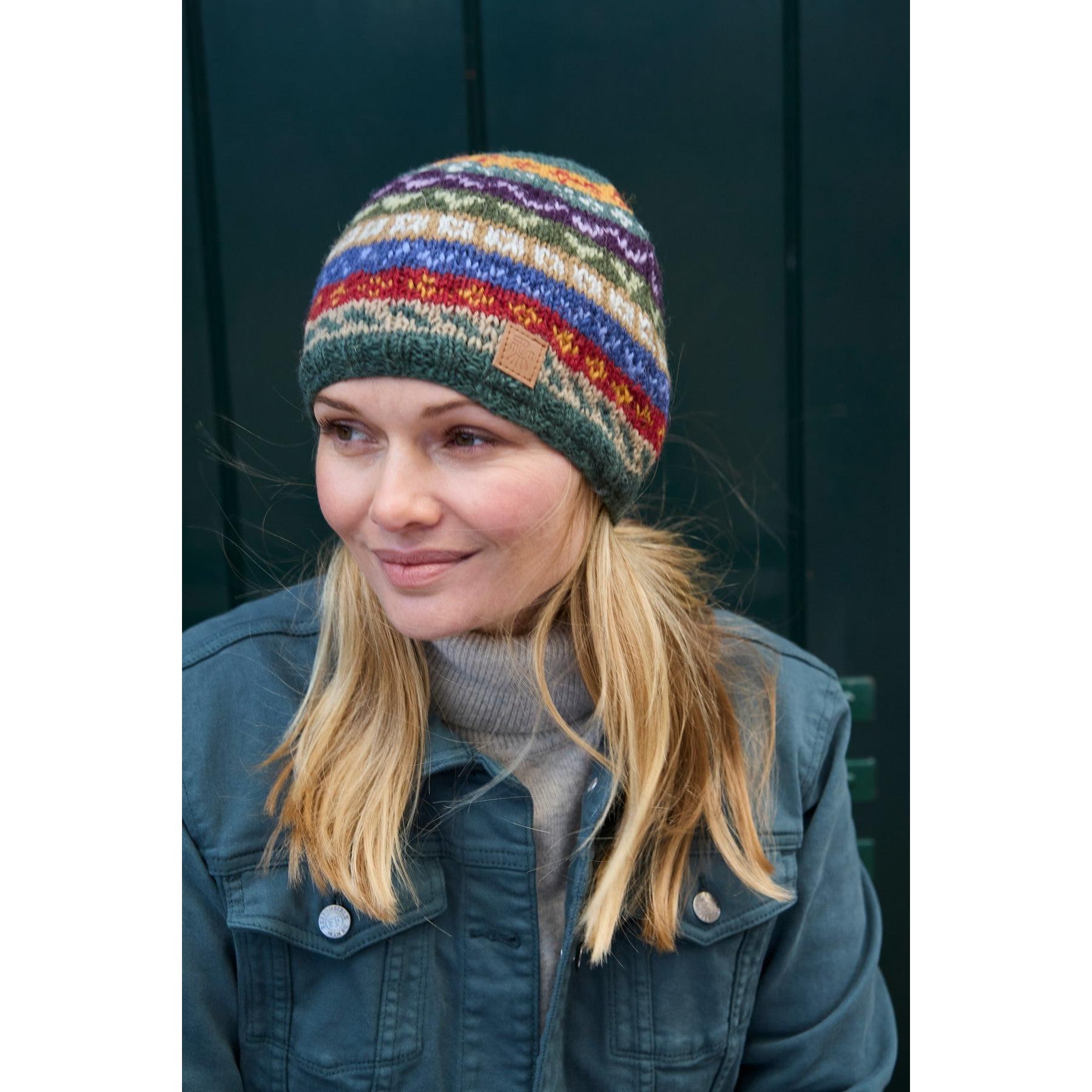Woman wearing a colorful Pachamama Elveden Beanie with patterned knit design and leather patch, outdoor winter fashion.