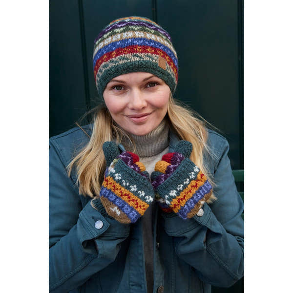 Woman wearing a colorful Pachamama Elveden beanie and patterned knitted gloves, smiling outdoors.