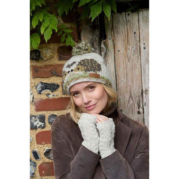 Woman wearing a Pachamama Hedgehog bobble beanie with nature-inspired design, cream and brown colors, and a pom-pom on top.