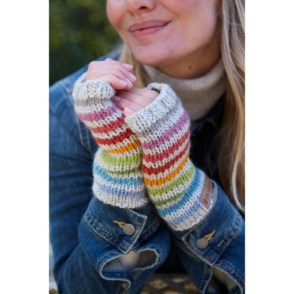 Pachamama Hoxton Stripe Handwarmer in multicolored stripes, made from pure Merino wool, worn by a woman outdoors.