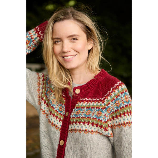 Woman wearing a red Pachamama Iona Cardigan with colorful Fair Isle pattern, wooden buttons, outdoors.