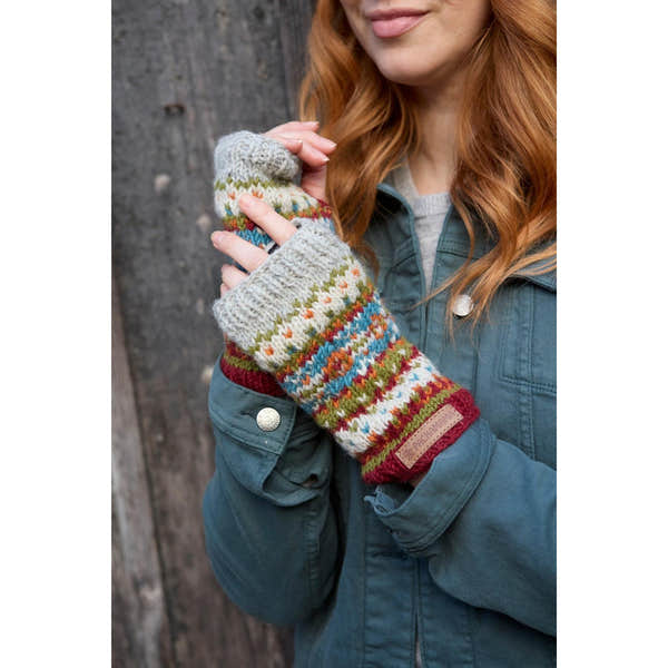 Pachamama Iona Handwarmer Burgundy, knitted multicolor wool handwarmer with a leather logo patch, worn by a woman against a wooden background.