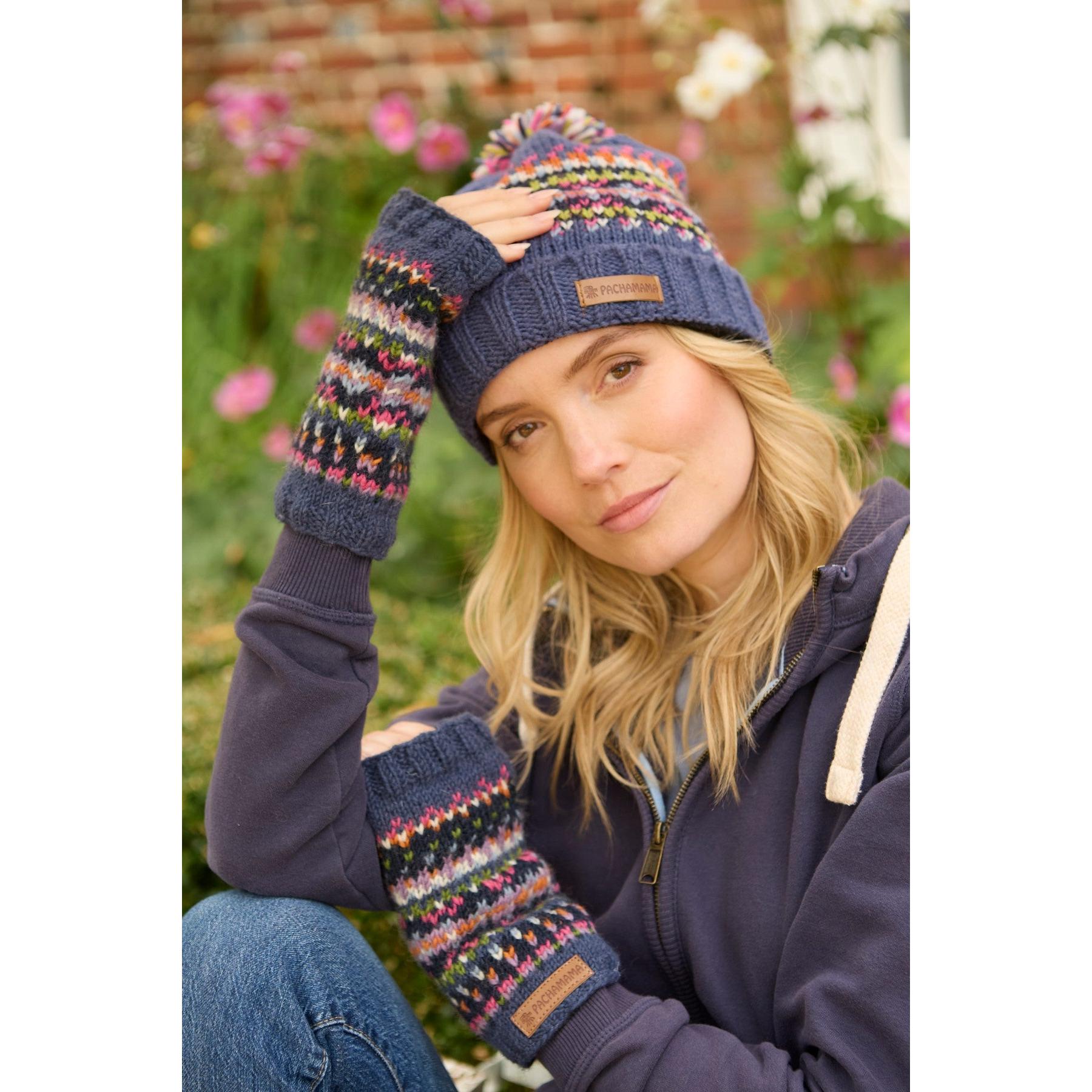 Pachamama Iona Handwarmer Denim set with colorful knit pattern, matching beanie and arm warmers, worn by a woman outdoors.