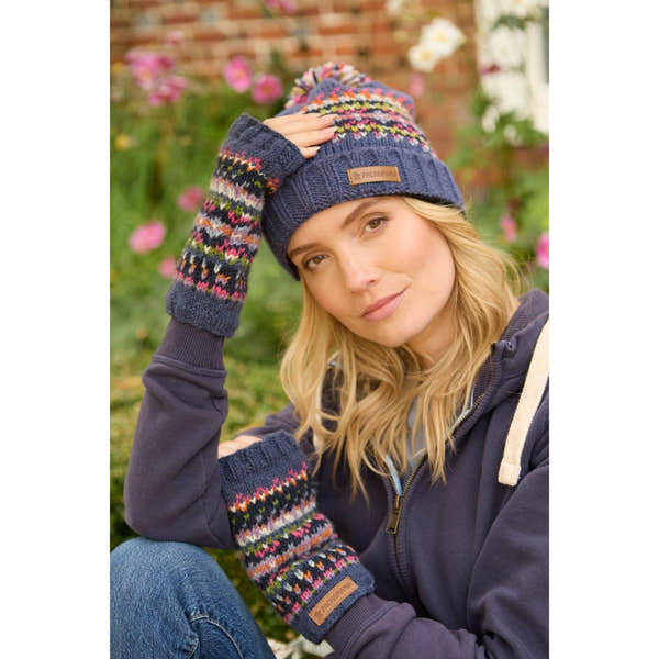Pachamama Iona Handwarmer Denim set with colorful knit pattern, matching beanie and arm warmers, worn by a woman outdoors.