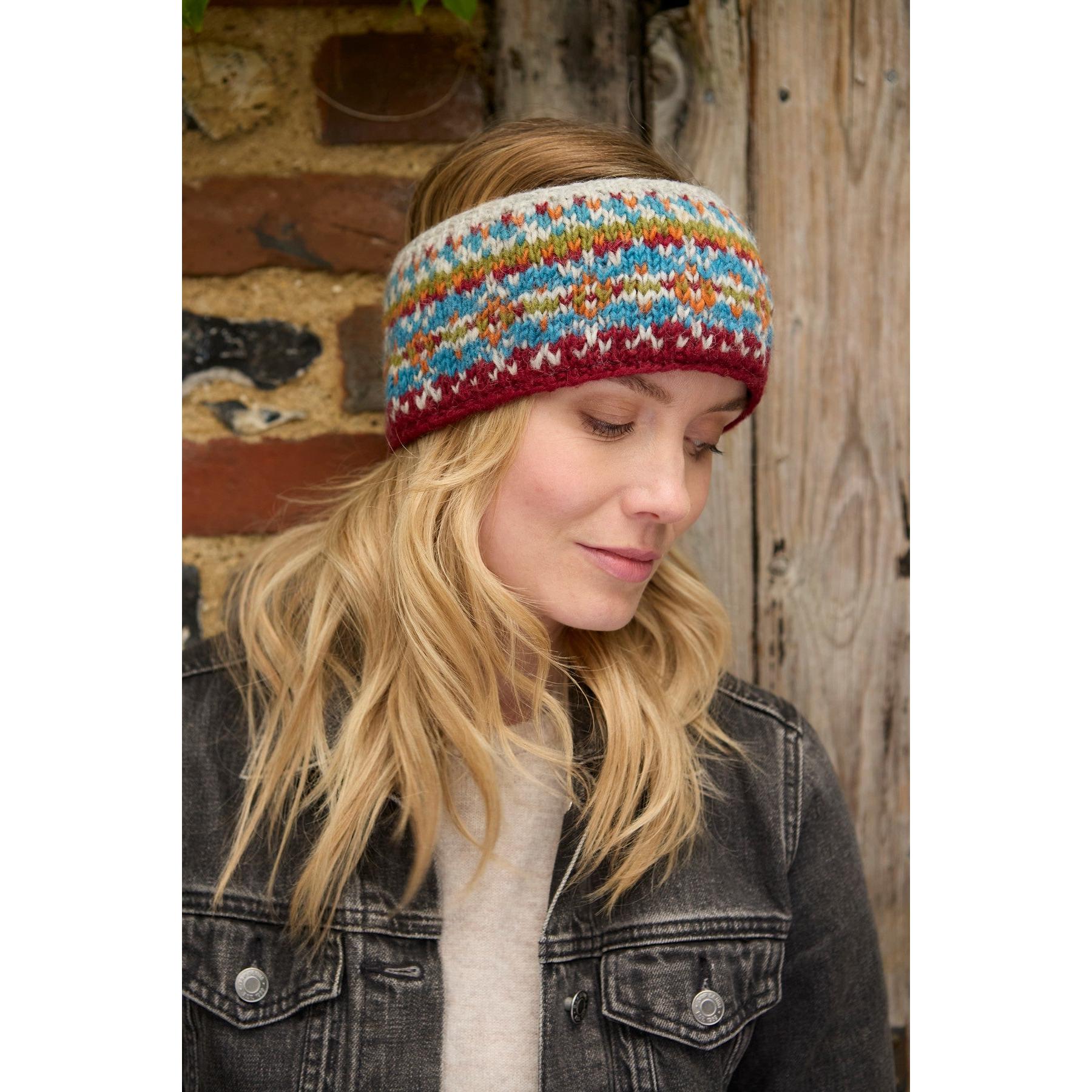 Pachamama Iona Headband Burgundy, colorful knit headband with traditional pattern, cozy accessory for winter, worn by woman with blonde hair.