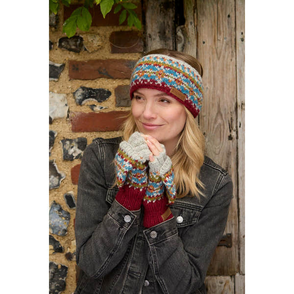 Woman wearing burgundy Pachamama Iona knit headband and matching patterned gloves outdoors.