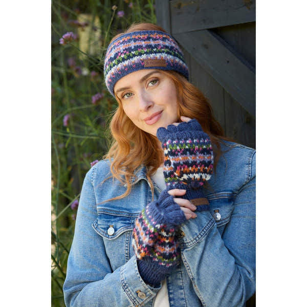 Pachamama Iona denim headband and fingerless gloves set with colorful knit pattern, worn by a woman outdoors.