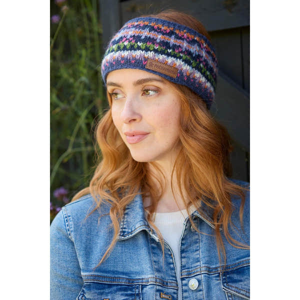 Pachamama Iona denim headband with colorful knit pattern, worn by a woman outdoors, featuring a leather logo patch.
