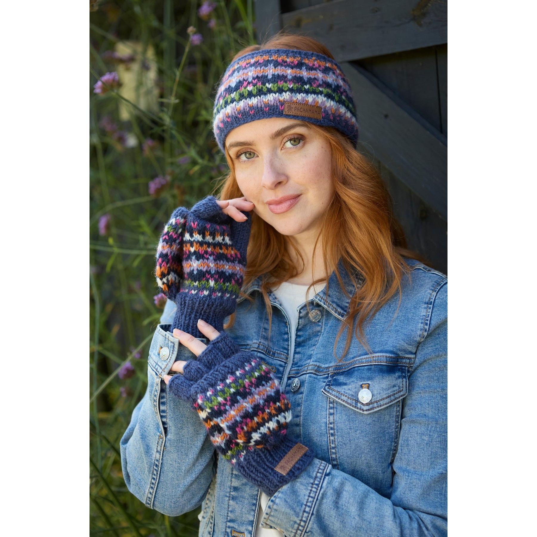 Pachamama Iona Headband Denim with multicolored knit pattern, paired with matching fingerless gloves, worn by a woman outdoors.