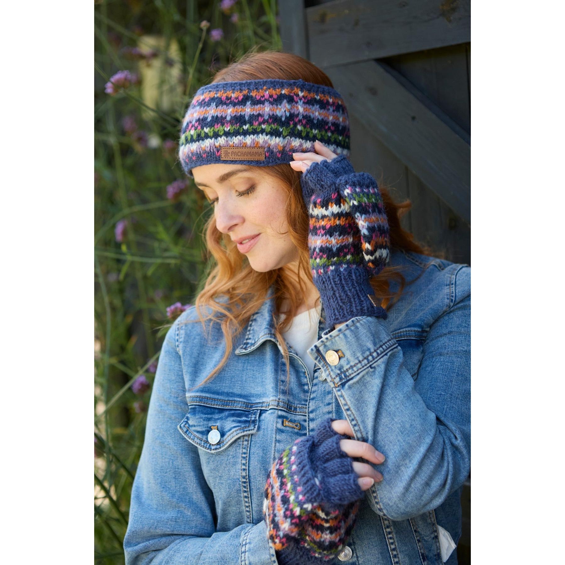 Pachamama Iona denim headband and fingerless gloves with colorful knitted pattern, worn by woman outdoors.