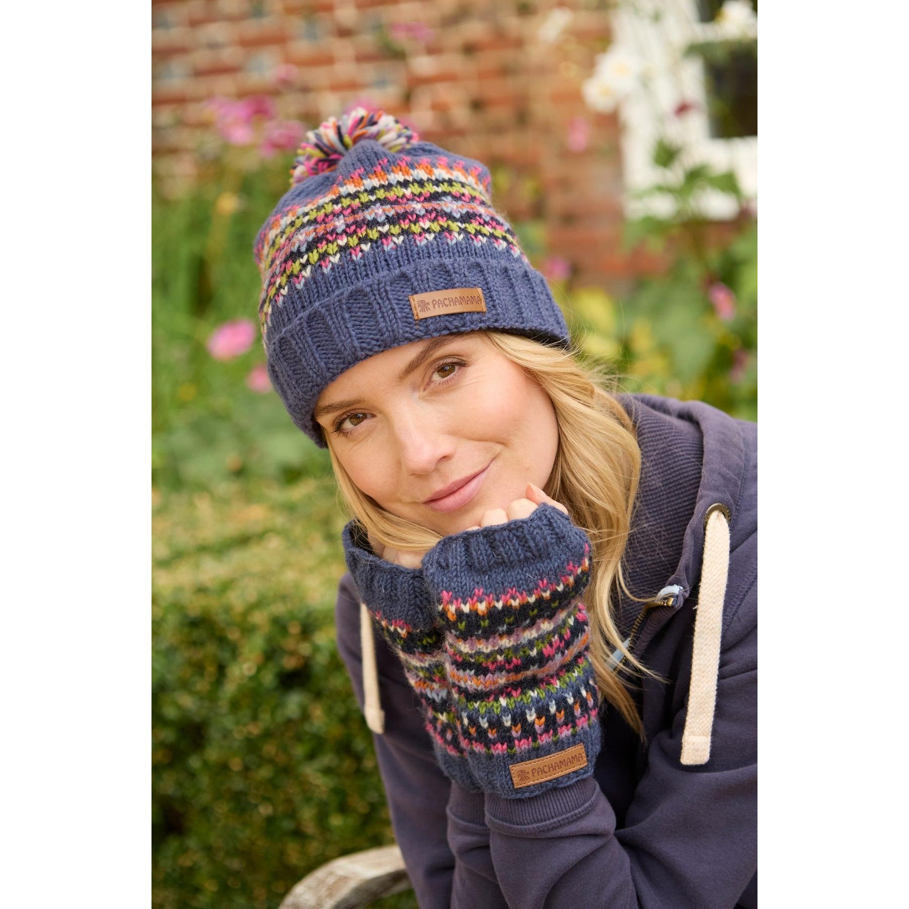 Woman wearing a denim Pachamama Iona Roll Back Bobble Beanie and matching patterned fingerless gloves outdoors.