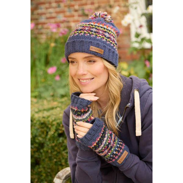 Pachamama Iona Roll Back Bobble Beanie Denim with colorful knit pattern and pom pom, worn by a woman outdoors.