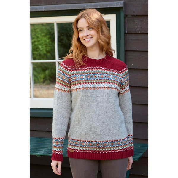 Pachamama Iona Burgundy sweater with intricate multicolored Fair Isle pattern on shoulders, sleeves, and hem, against dark wood background.