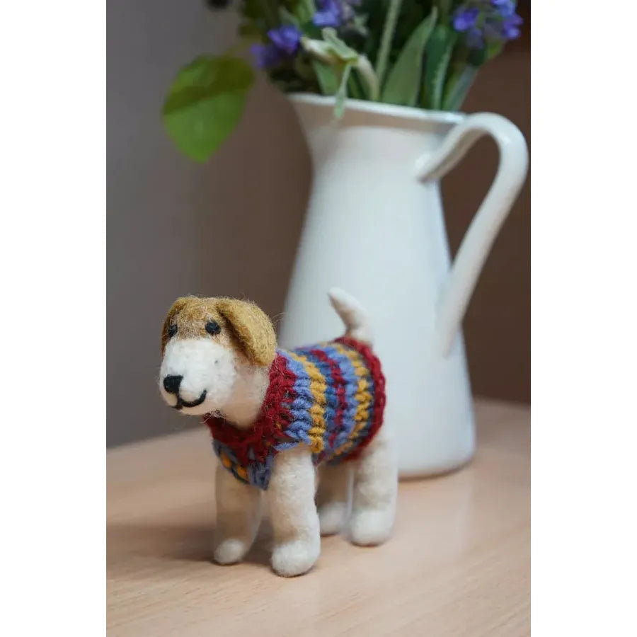 Felt Dachshund plush toy wearing a colorful jumper, with white vase of purple flowers in background.