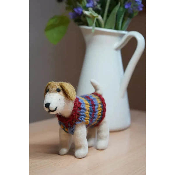 Felt Dachshund plush toy wearing a colorful jumper, with white vase of purple flowers in background.