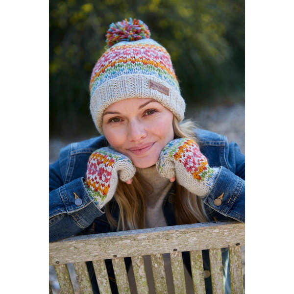 Woman wearing Pachamama Killarney Pure Merino oatmeal bobble beanie and matching mittens outdoor.