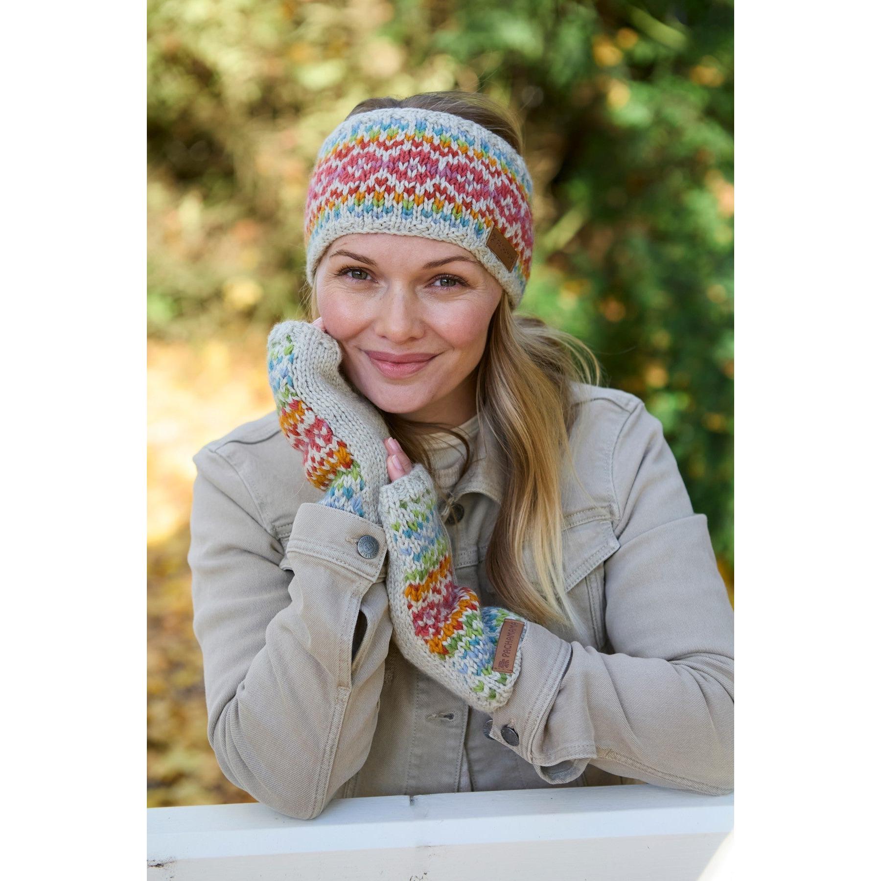 Woman wearing Pachamama Killarney handwarmer and headband in multicolor merino wool, outdoors with autumn background.