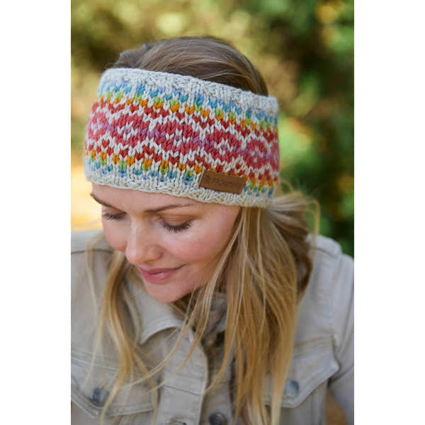 Pachamama Killarney Headband in oatmeal with colorful Fair Isle knit pattern, made of pure merino wool, worn by a woman outdoors.