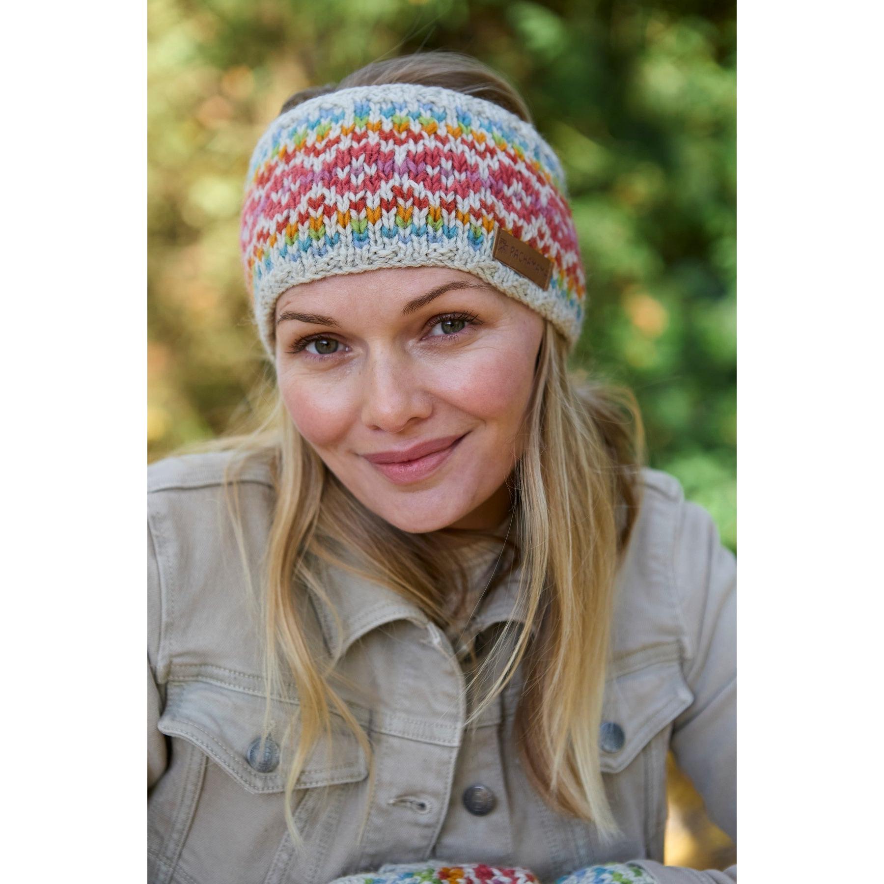 Pachamama Killarney Headband in Oatmeal with colorful knit pattern, worn by smiling woman outdoors. Pure Merino wool, cozy winter accessory.
