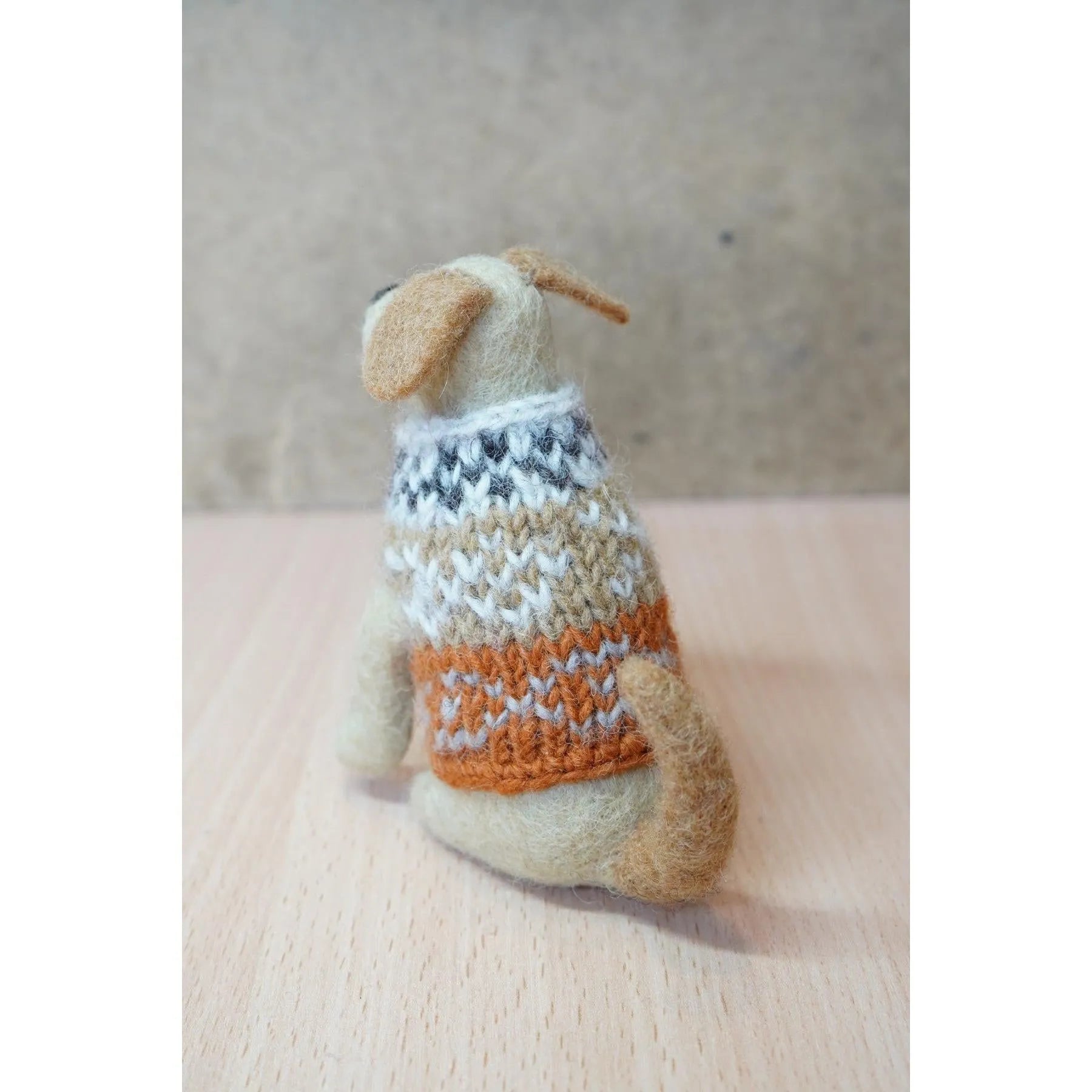 Felted Labrador dog figurine wearing a multicolored knitted sweater, handmade craft, beige and brown tones.
