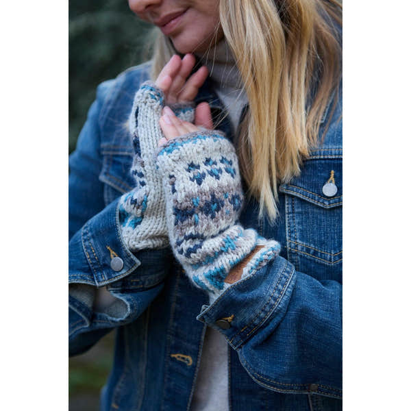 Pachamama Loch Fyne Pure Merino blue handwarmer gloves worn by a woman in a denim jacket, outdoors.
