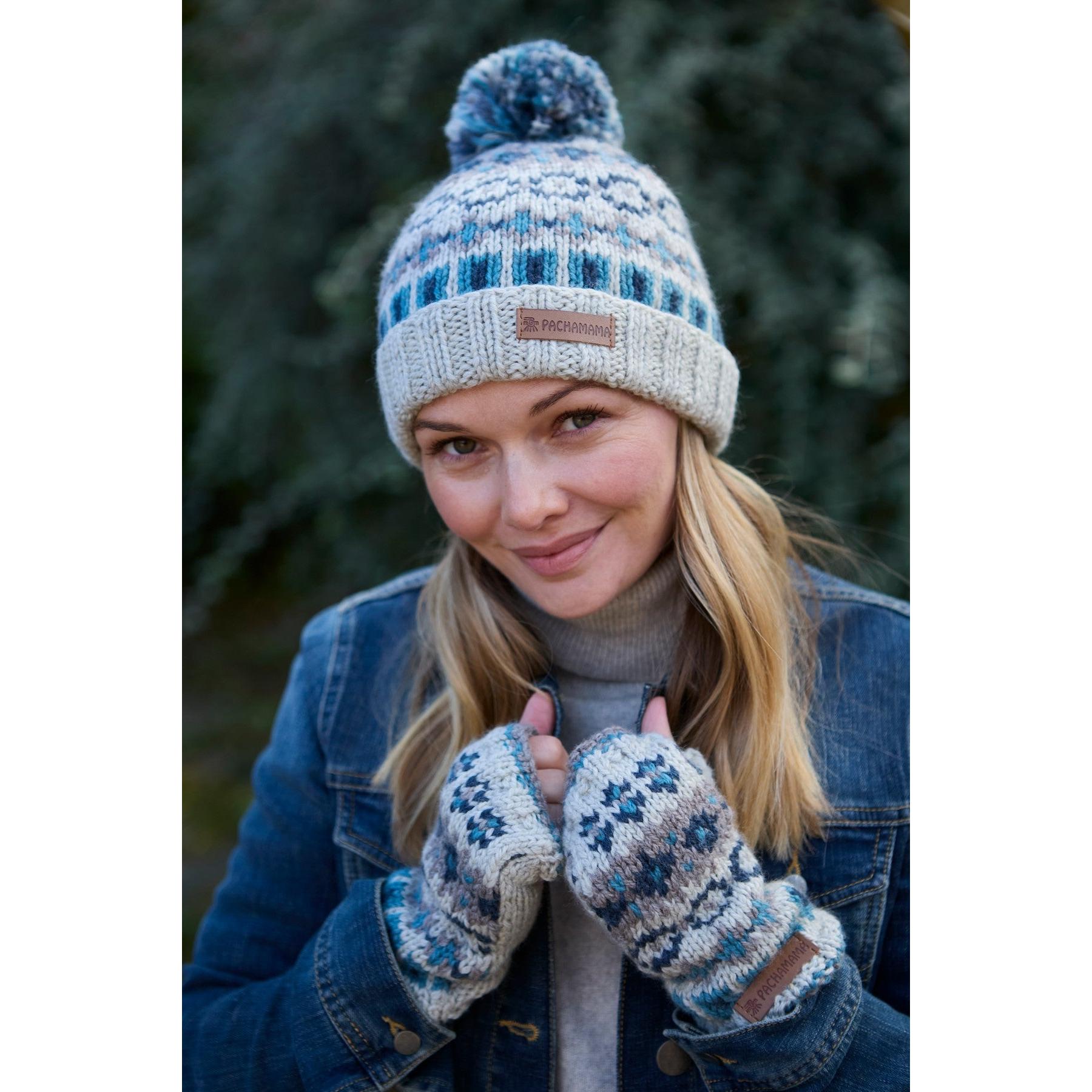 Woman wearing blue and white Pachamama Loch Fyne Pure Merino handwarmer hat and gloves outdoors.