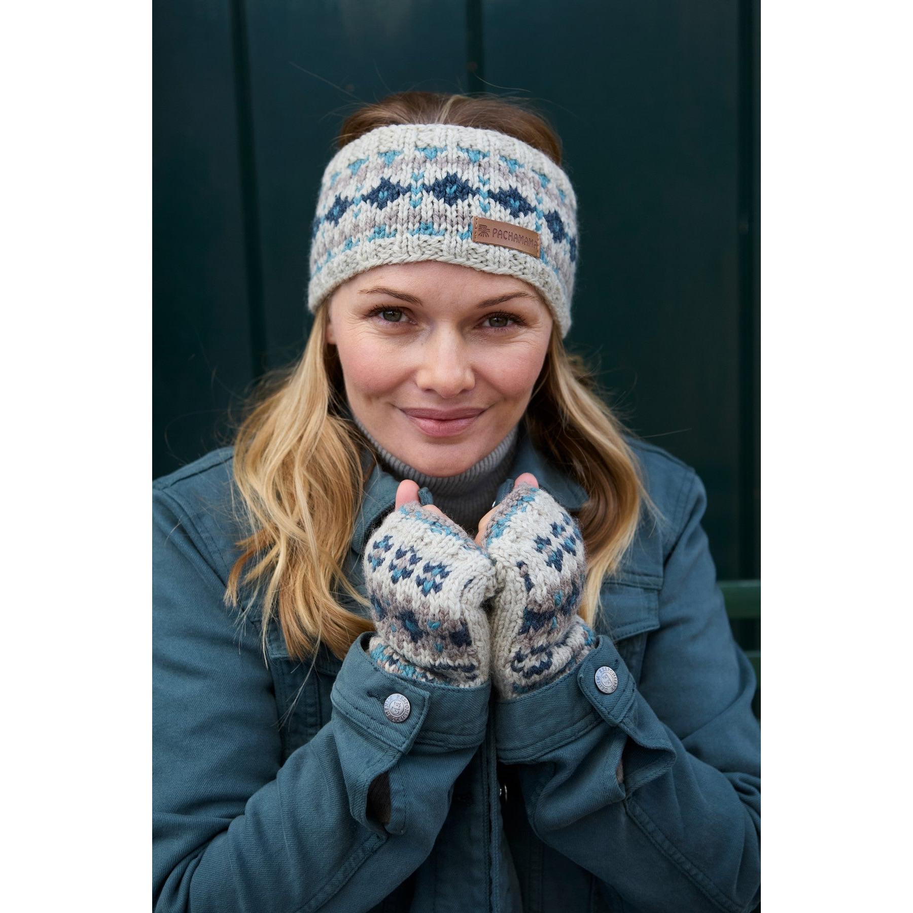 Woman wearing blue Pachamama Loch Fyne merino headband and matching gloves, smiling outdoors.