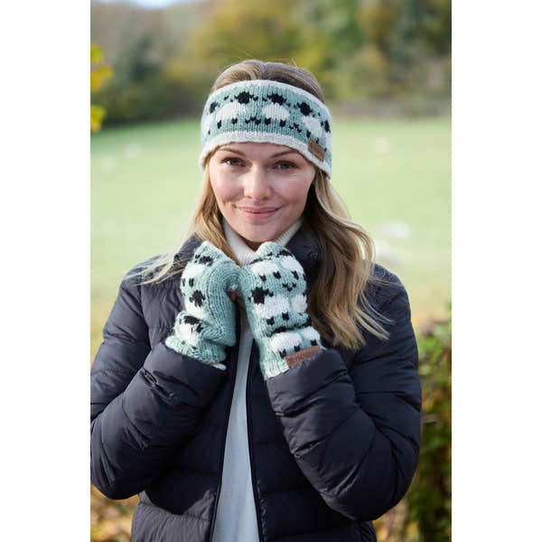 Woman wearing green Pachamama Merino sheep knit headband and mittens outdoors in fall.