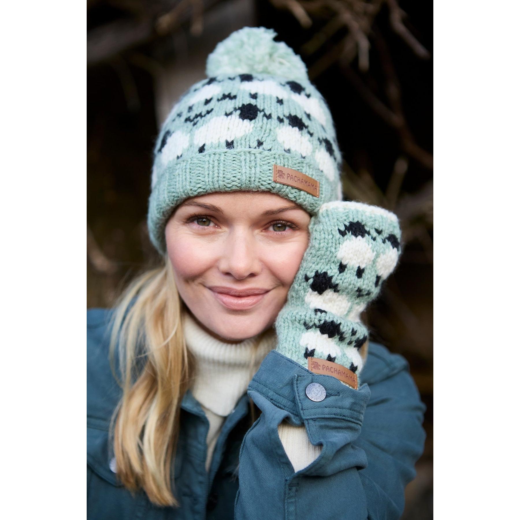 Green Pachamama Merino Sheep Roll Back Bobble Beanie and matching mittens for women, soft wool knit with sheep pattern and pom-pom detail.