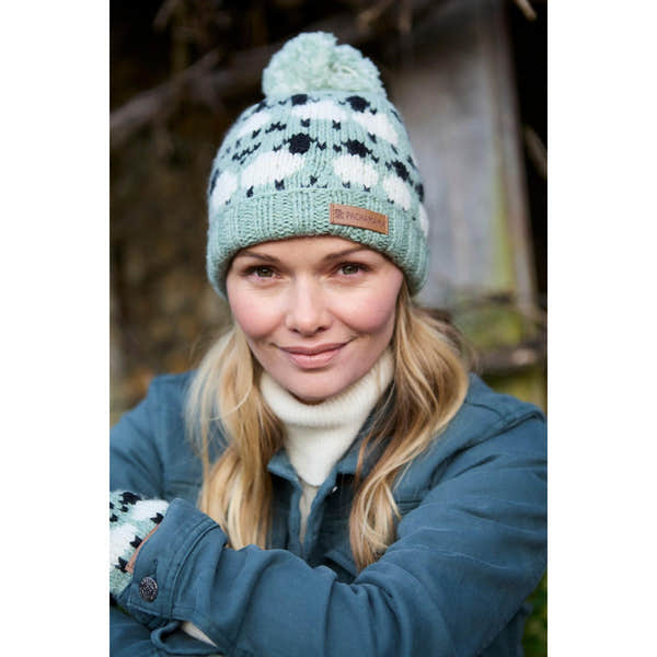 Pachamama Merino Sheep Roll Back Bobble Beanie in green with pom, featuring knit sheep pattern and leather logo patch.