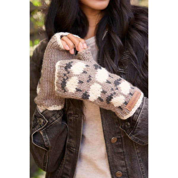 Pachamama Merino sheep handwarmer with mushroom design, beige and black colors, fuzzy knit texture, held by a woman outdoors.