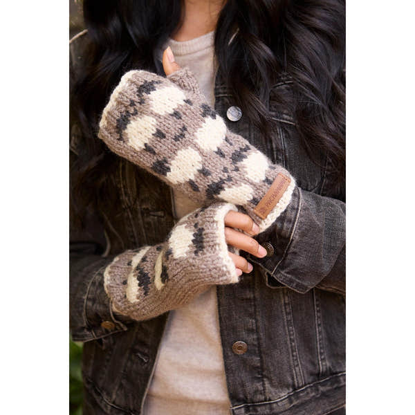 Pachamama Merino sheep handwarmer mushroom-patterned knitted glove worn by a person with a denim jacket.